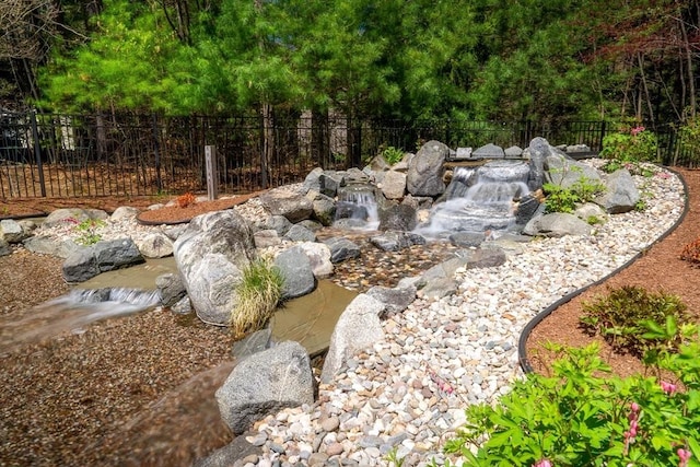 view of yard featuring a garden pond and fence