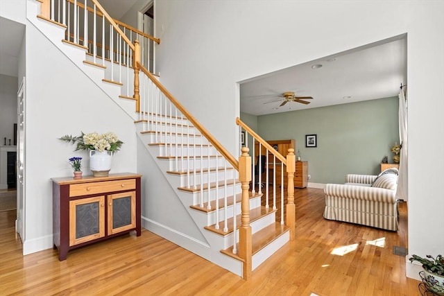 staircase with baseboards, ceiling fan, and wood finished floors