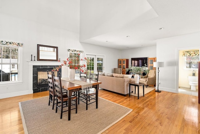 dining space with a fireplace, baseboards, a healthy amount of sunlight, and light wood-style floors