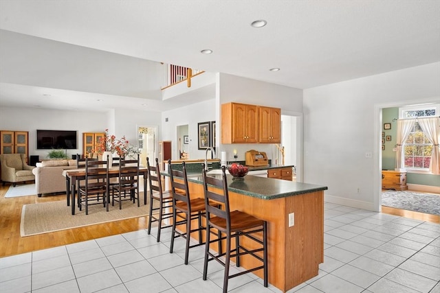kitchen with a kitchen bar, dark countertops, baseboards, recessed lighting, and light tile patterned flooring