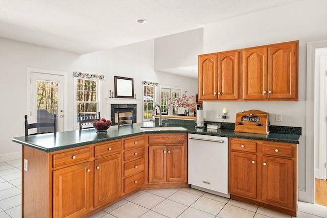 kitchen with a peninsula, white dishwasher, brown cabinets, a sink, and light tile patterned floors