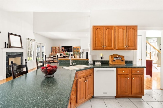 kitchen featuring brown cabinets, a peninsula, light tile patterned floors, and dishwasher