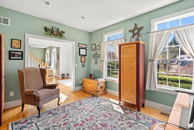 living area with visible vents, light wood-style flooring, and a wealth of natural light