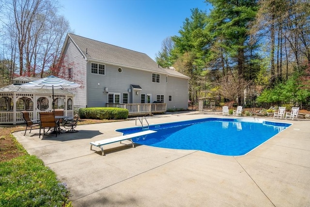 pool with a gazebo, a diving board, a patio area, and a wooden deck