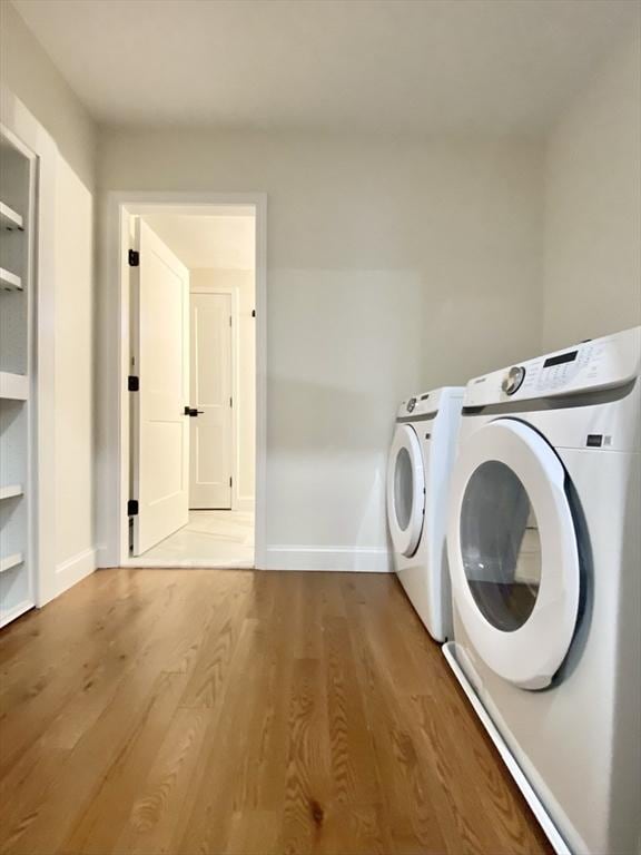 clothes washing area featuring built in shelves, wood-type flooring, and washing machine and clothes dryer