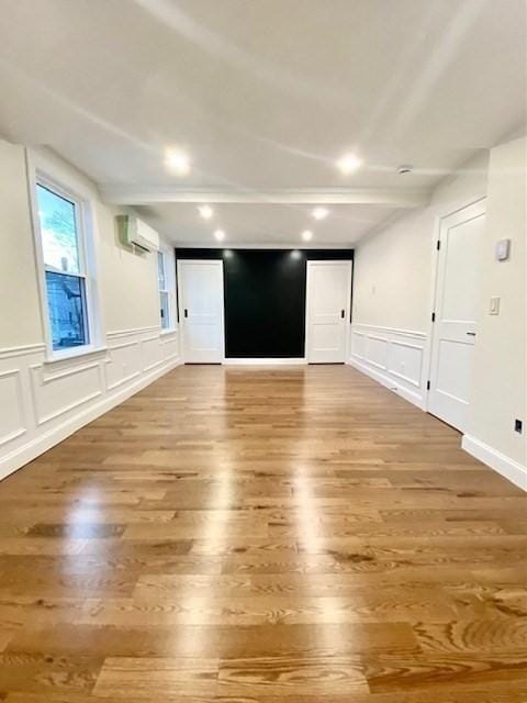 unfurnished room with hardwood / wood-style flooring and an AC wall unit