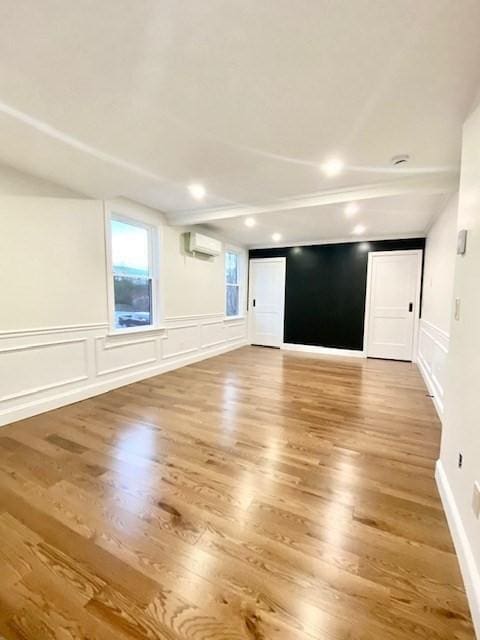 spare room featuring hardwood / wood-style floors and an AC wall unit