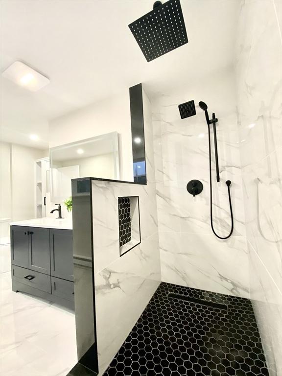 bathroom featuring tiled shower and vanity