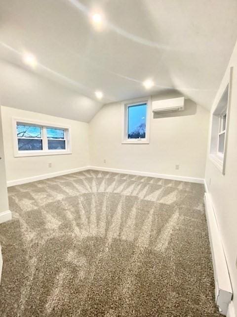 bonus room featuring lofted ceiling, a wealth of natural light, a wall unit AC, and carpet