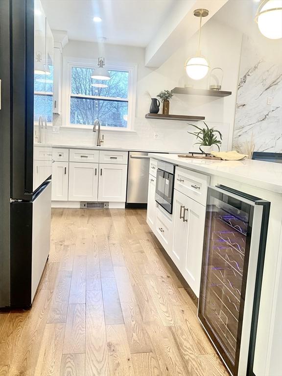 kitchen featuring wine cooler, dishwasher, white cabinets, and light wood-type flooring