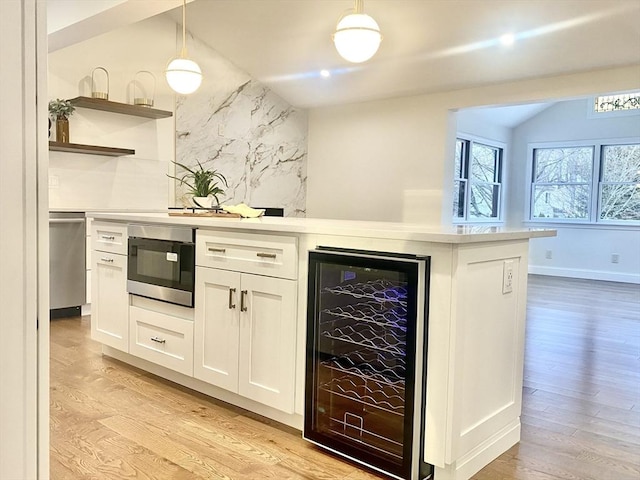 kitchen featuring stainless steel microwave, decorative light fixtures, white cabinets, wine cooler, and backsplash