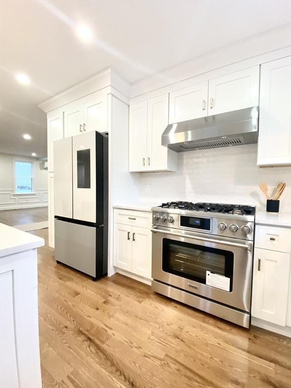 kitchen with white cabinetry, refrigerator, and gas stove