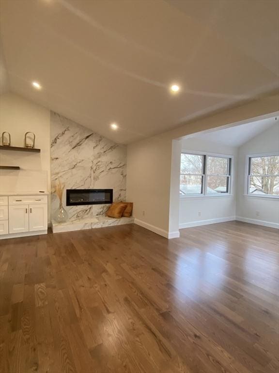 unfurnished living room with a premium fireplace, vaulted ceiling, and dark hardwood / wood-style floors