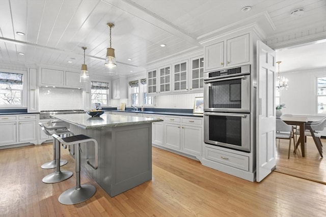 15 Alden Rd, Wellesley, MA 02481 - kitchen featuring stainless steel double oven, light wood-style floors, dark countertops, white cabinets, and a kitchen island