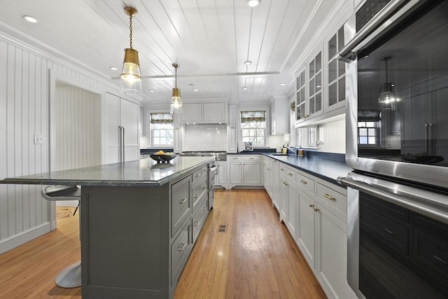 15 Alden Rd, Wellesley, MA 02481 - kitchen with dark countertops, light wood-style flooring, a breakfast bar area, glass insert cabinets, and ornamental molding