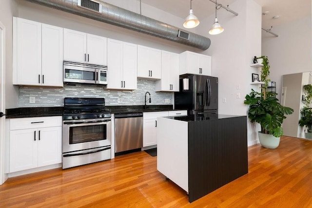 960 Broadway Unit 10, Chelsea, MA 02150 - kitchen featuring appliances with stainless steel finishes, tasteful backsplash, dark countertops, a high ceiling, and white cabinets