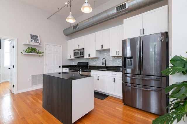 960 Broadway Unit 10, Chelsea, MA 02150 - kitchen featuring appliances with stainless steel finishes, dark countertops, tasteful backsplash, light wood-type flooring, and white cabinets