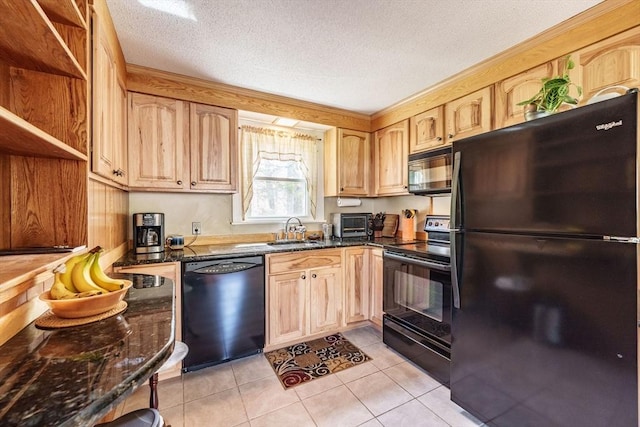 kitchen featuring dark stone counters, light tile patterned flooring, a sink, and black appliances