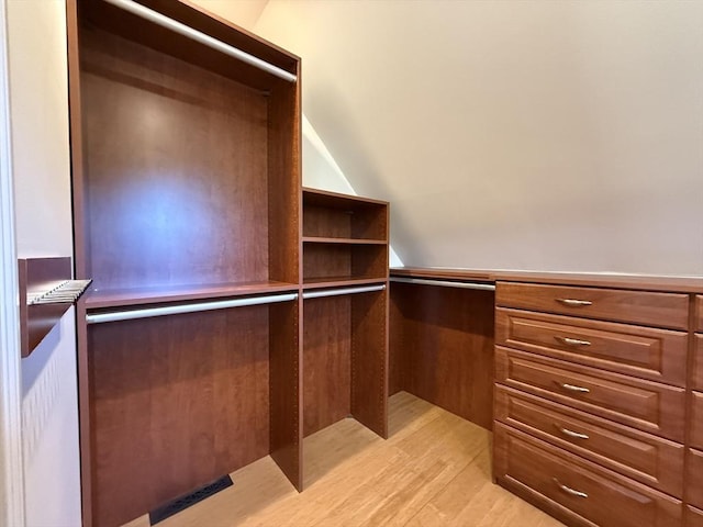 walk in closet featuring vaulted ceiling and light wood-style floors