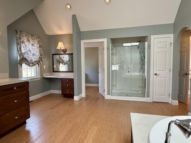 bathroom featuring wood finished floors, a shower stall, vanity, baseboards, and lofted ceiling