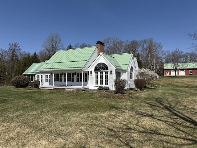 back of property with metal roof, a lawn, and a chimney