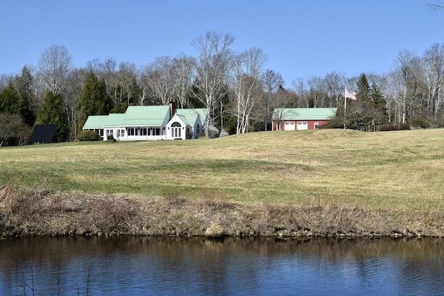 exterior space featuring a yard, a water view, and metal roof