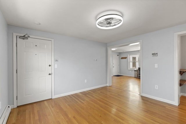 spare room with ceiling fan, light wood-type flooring, and a baseboard heating unit