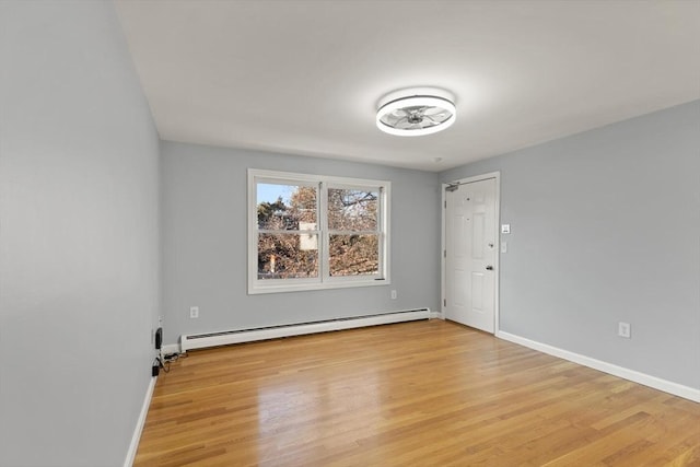 spare room featuring a baseboard radiator and light hardwood / wood-style floors