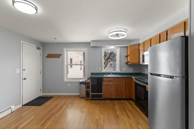 kitchen featuring light hardwood / wood-style flooring, black appliances, a baseboard radiator, and sink