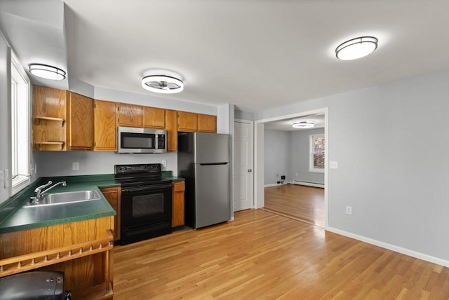 kitchen with appliances with stainless steel finishes, light wood-type flooring, a baseboard heating unit, and sink