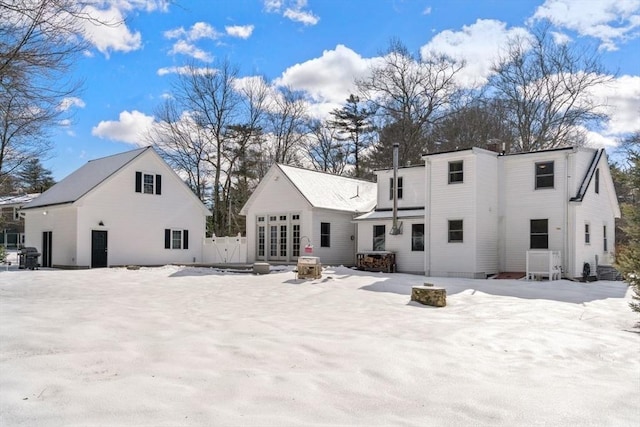 snow covered house featuring an outdoor fire pit and french doors