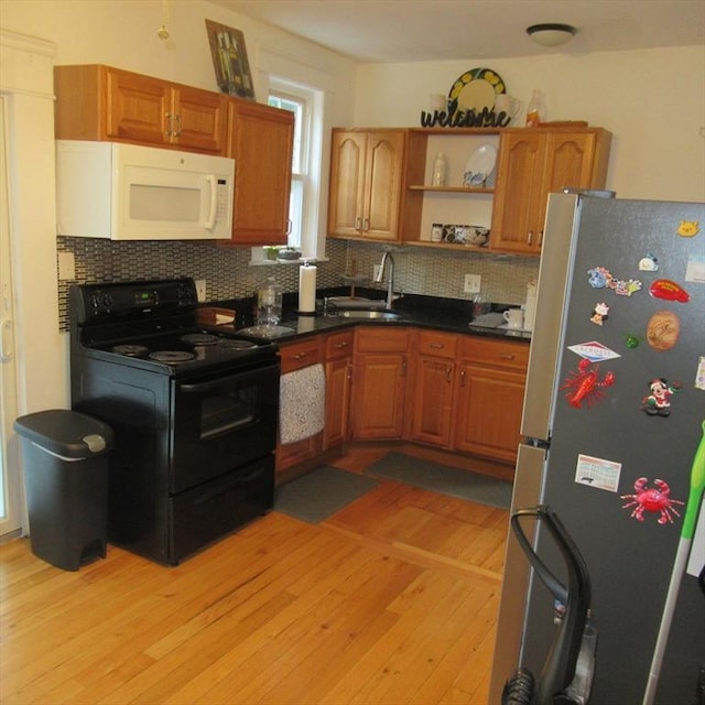 85-87 Belrose Ave, Lowell, MA 01852 - kitchen featuring black range with electric stovetop, freestanding refrigerator, white microwave, decorative backsplash, and light wood-style floors