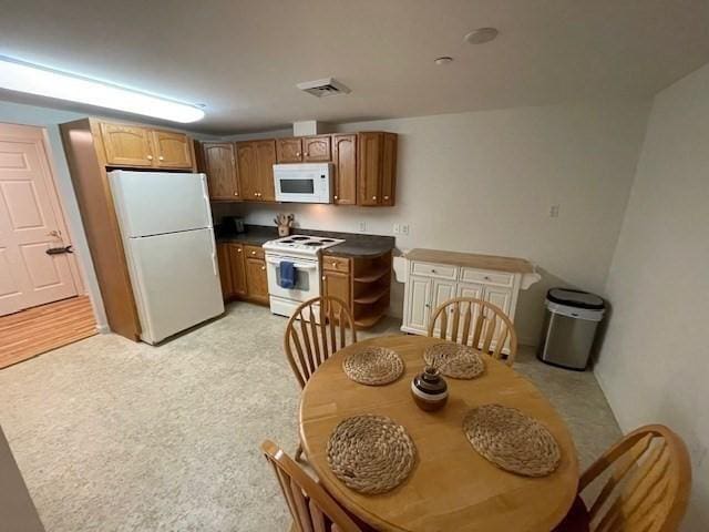 kitchen featuring white appliances, dark countertops, and brown cabinets