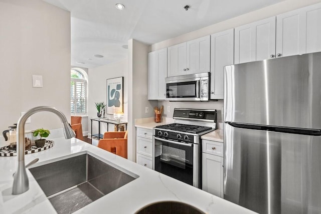 1682 Washington St Unit 8, Boston, MA 02118 - kitchen with appliances with stainless steel finishes, white cabinetry, light stone counters, and recessed lighting