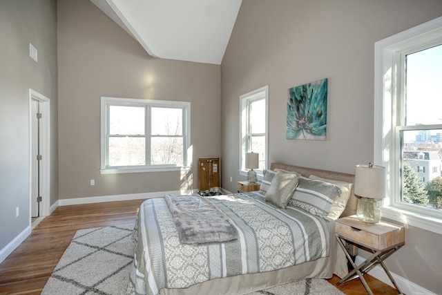 bedroom featuring wood-type flooring and high vaulted ceiling