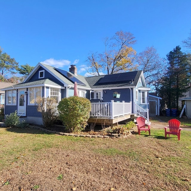 rear view of house featuring a wooden deck, a yard, and solar panels