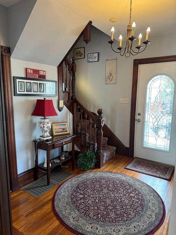 entryway featuring an inviting chandelier, hardwood / wood-style floors, and vaulted ceiling