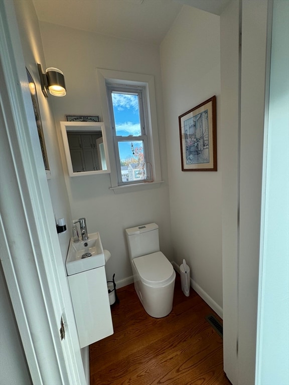 bathroom with toilet, vanity, and wood-type flooring