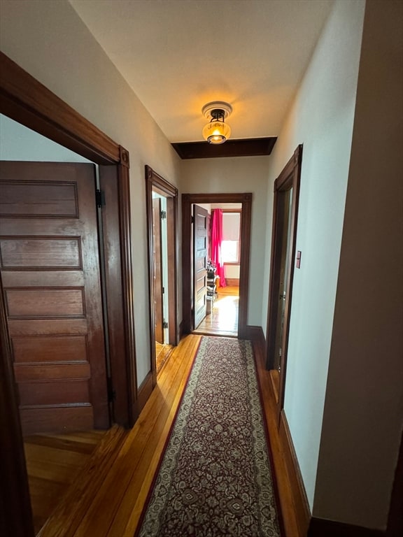 corridor with hardwood / wood-style flooring