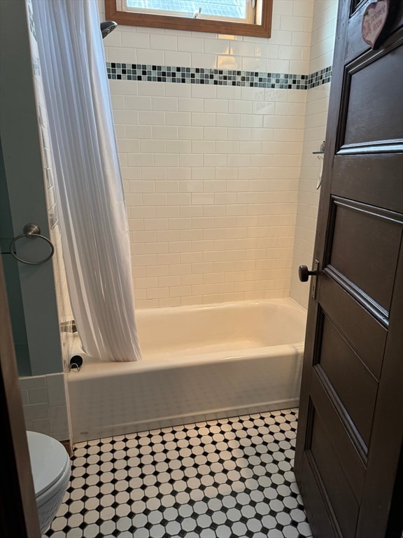 bathroom featuring toilet and shower / bathtub combination with curtain