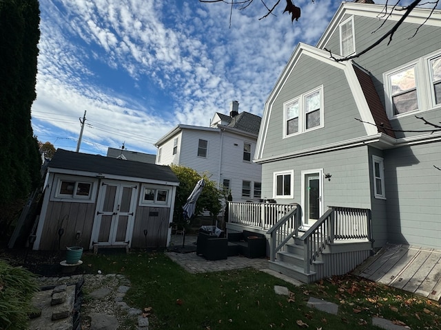 rear view of property with a wooden deck and a storage shed