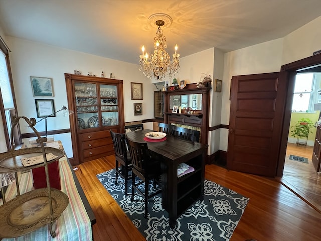 dining room with wood-type flooring and a notable chandelier