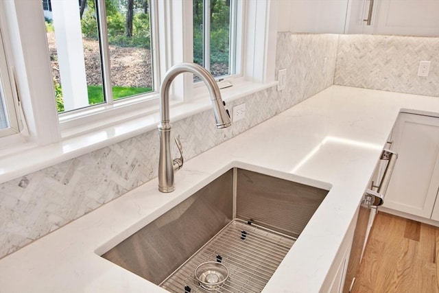 1 Wilsons Ln, Edgartown, MA 02539 - kitchen view of a sink, tasteful backsplash, white cabinetry, and light stone counters