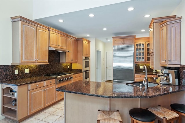 kitchen with a breakfast bar, stainless steel appliances, a sink, a peninsula, and under cabinet range hood