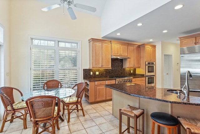 kitchen featuring decorative backsplash, a breakfast bar area, stainless steel appliances, under cabinet range hood, and a sink