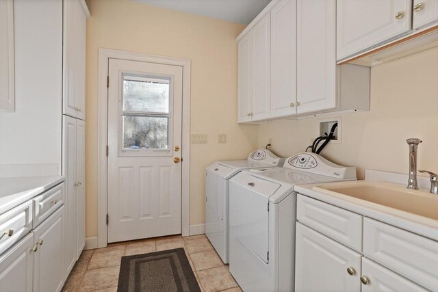 laundry area with light tile patterned flooring, washing machine and dryer, a sink, baseboards, and cabinet space