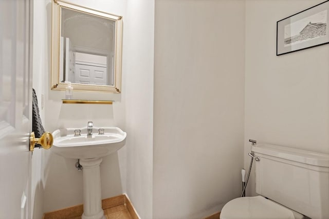 bathroom featuring toilet, baseboards, and a sink