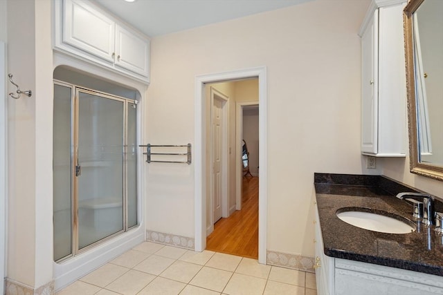 bathroom with a stall shower, tile patterned flooring, baseboards, and vanity