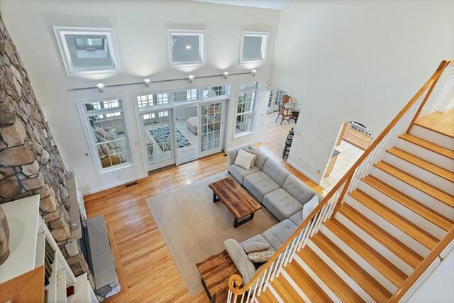 living area featuring light wood-style floors, baseboards, stairway, and a high ceiling