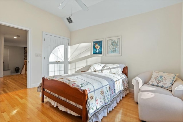 bedroom with lofted ceiling, light wood-style flooring, visible vents, baseboards, and a closet